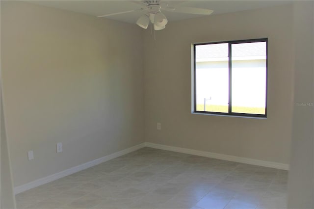 spare room with ceiling fan and light tile floors