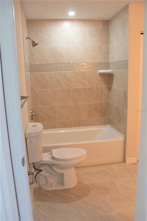 bathroom with tile flooring, toilet, and tiled shower / bath