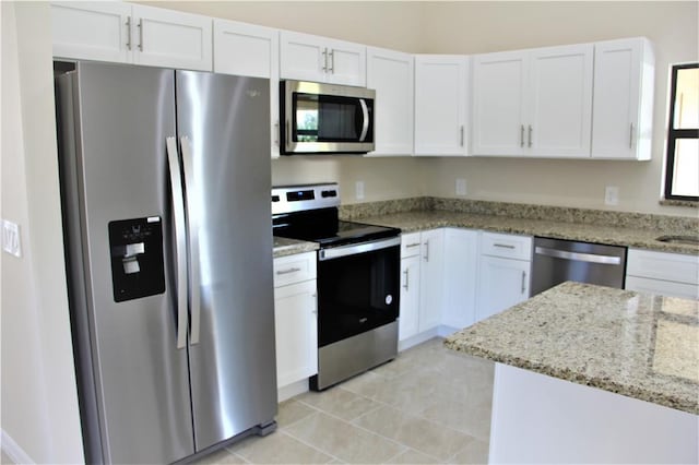 kitchen with appliances with stainless steel finishes, light stone countertops, white cabinetry, and light tile flooring