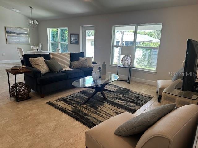 tiled living room featuring a notable chandelier, vaulted ceiling, and a wealth of natural light