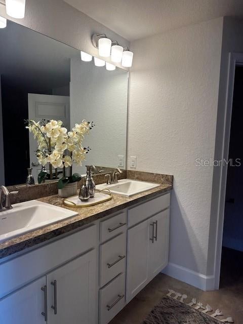 bathroom featuring double vanity, a sink, and a textured wall