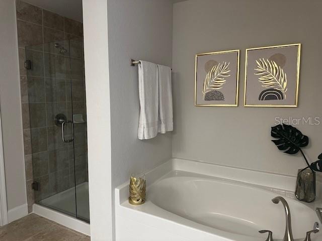 full bathroom featuring a shower stall, a bath, and tile patterned floors