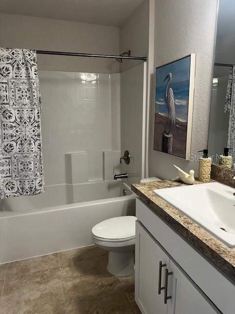 bathroom with shower / tub combo, a textured wall, vanity, and toilet