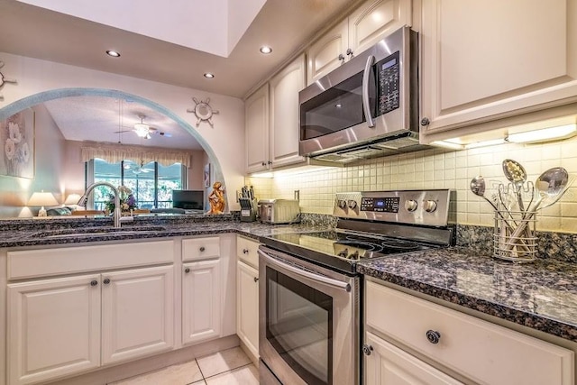 kitchen featuring dark stone countertops, stainless steel appliances, sink, and white cabinets