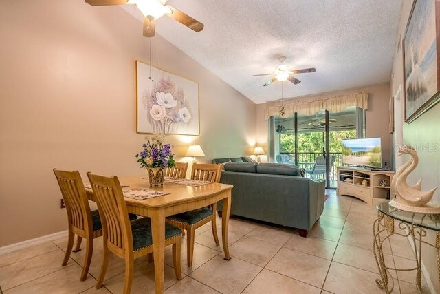 dining room featuring light tile patterned flooring, ceiling fan, lofted ceiling, and a textured ceiling