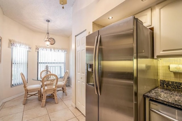 kitchen with decorative backsplash, hanging light fixtures, light tile patterned floors, stainless steel appliances, and a textured ceiling