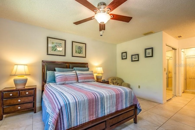 bedroom with ceiling fan, light tile patterned floors, and a textured ceiling