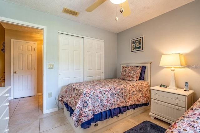 tiled bedroom with ceiling fan, a textured ceiling, and a closet