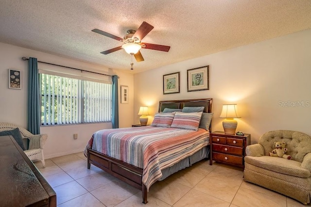 bedroom with ceiling fan, light tile patterned floors, and a textured ceiling