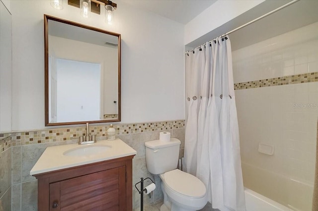 full bathroom with toilet, vanity, tile walls, and shower / tub combo with curtain