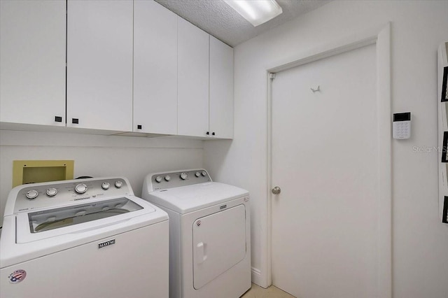 laundry room featuring cabinets, a textured ceiling, and separate washer and dryer