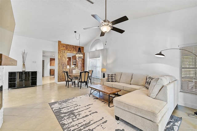 living room featuring tile patterned floors, lofted ceiling, and ceiling fan with notable chandelier