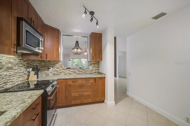 kitchen featuring backsplash, pendant lighting, appliances with stainless steel finishes, light tile patterned floors, and light stone counters