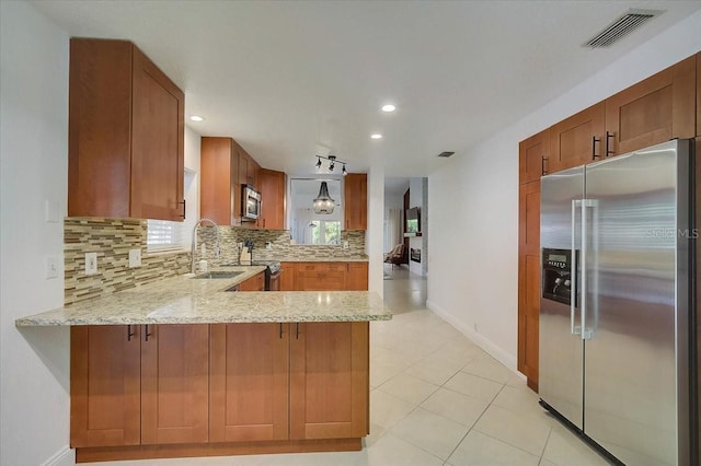 kitchen featuring kitchen peninsula, appliances with stainless steel finishes, backsplash, light stone countertops, and sink