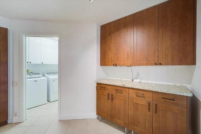 interior space with light tile patterned floors, independent washer and dryer, and light stone counters