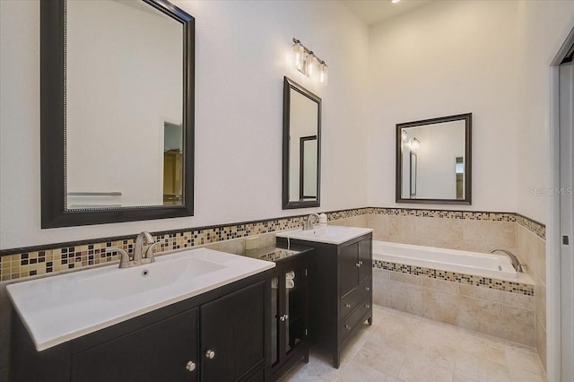 bathroom with tiled bath, vanity, and tile patterned flooring