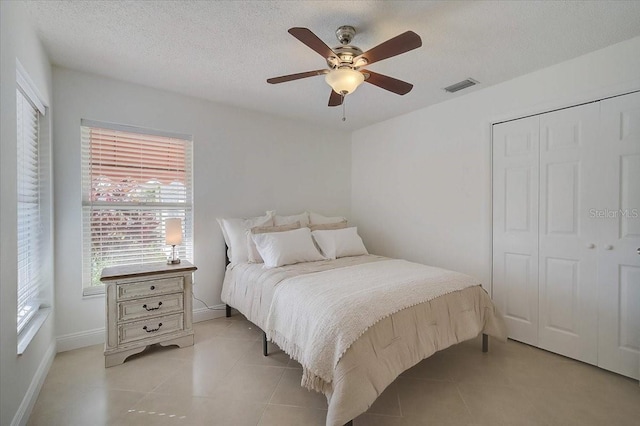 bedroom with a textured ceiling, ceiling fan, light tile patterned floors, and a closet