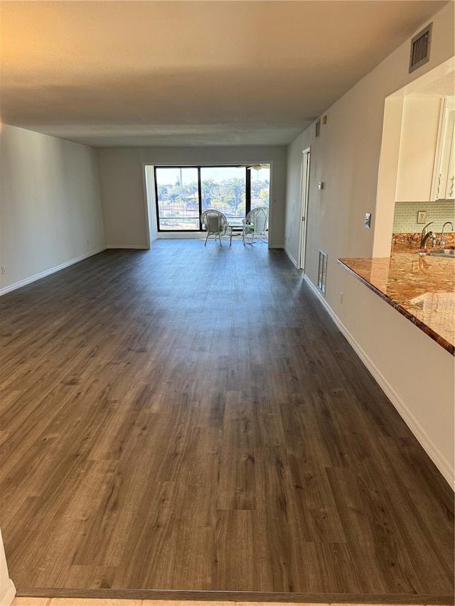 unfurnished living room featuring dark wood-type flooring and sink