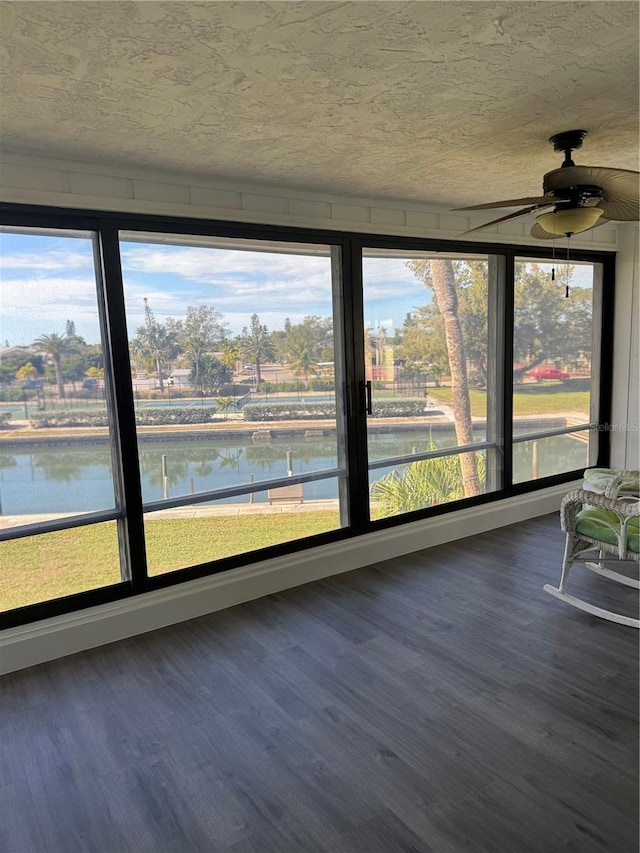 unfurnished sunroom featuring a water view and ceiling fan