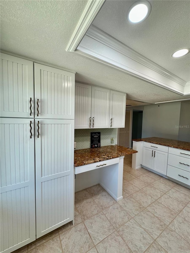 kitchen with tasteful backsplash, white cabinets, light tile patterned floors, crown molding, and a textured ceiling