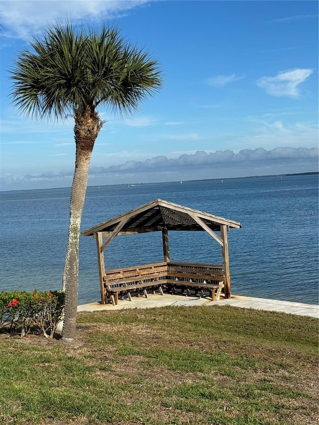 view of dock with a water view and a lawn