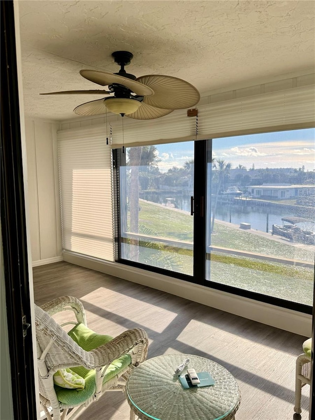 unfurnished sunroom with a water view and ceiling fan