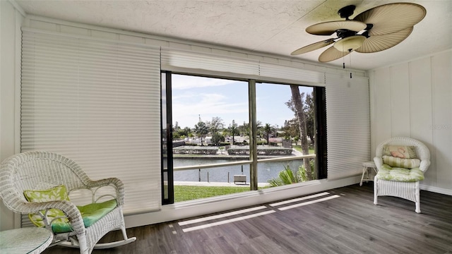 living area with a water view, dark hardwood / wood-style flooring, and ceiling fan