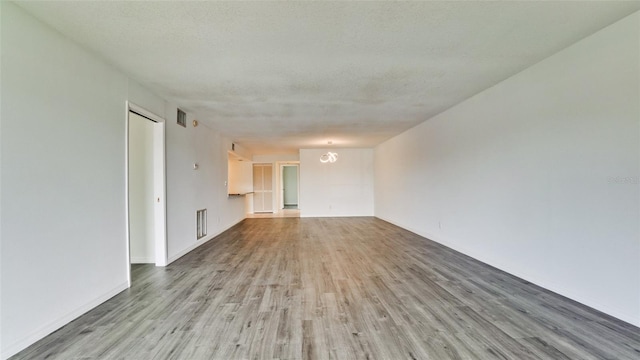 empty room featuring wood-type flooring and a textured ceiling