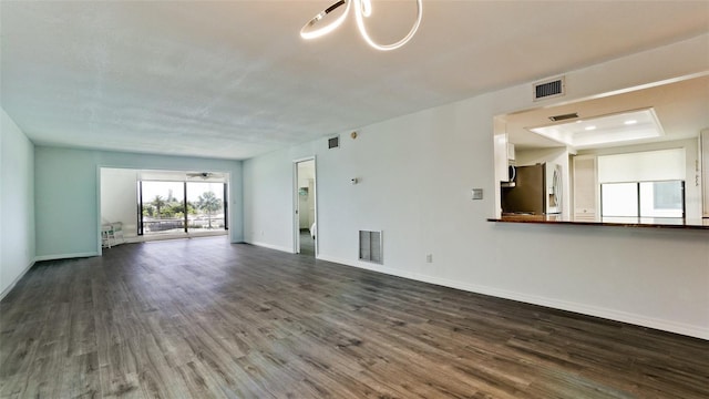 unfurnished living room featuring a tray ceiling and dark hardwood / wood-style flooring