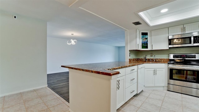 kitchen featuring light tile patterned flooring, white cabinetry, tasteful backsplash, appliances with stainless steel finishes, and kitchen peninsula