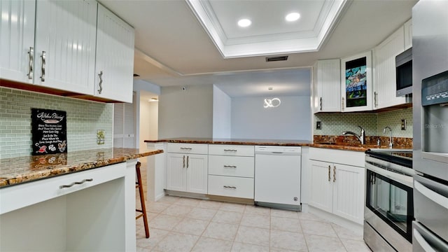 kitchen with white cabinetry, light tile patterned flooring, a tray ceiling, decorative backsplash, and appliances with stainless steel finishes