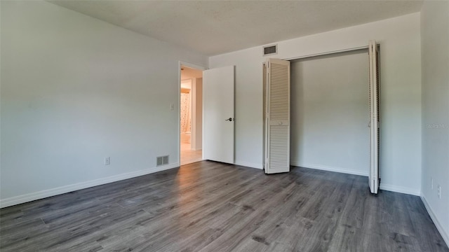 unfurnished bedroom featuring a closet and dark hardwood / wood-style floors