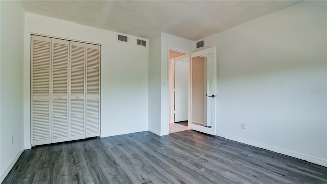 unfurnished bedroom with dark wood-type flooring and a closet