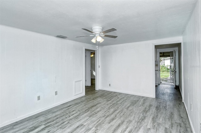 unfurnished room featuring light wood-type flooring, ceiling fan, and a textured ceiling