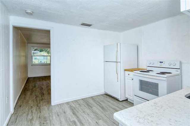 kitchen with light wood-type flooring, white appliances, white cabinets, and a textured ceiling