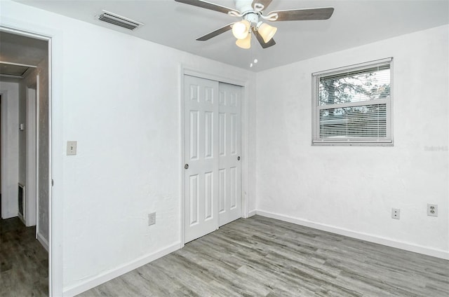 unfurnished bedroom with wood-type flooring, ceiling fan, and a closet