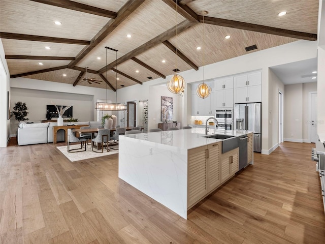 kitchen featuring appliances with stainless steel finishes, sink, white cabinets, a large island with sink, and hanging light fixtures