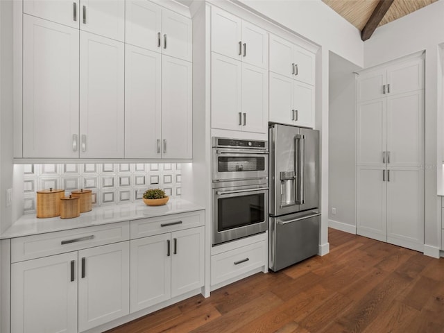 kitchen featuring white cabinetry, tasteful backsplash, lofted ceiling with beams, dark hardwood / wood-style flooring, and stainless steel appliances