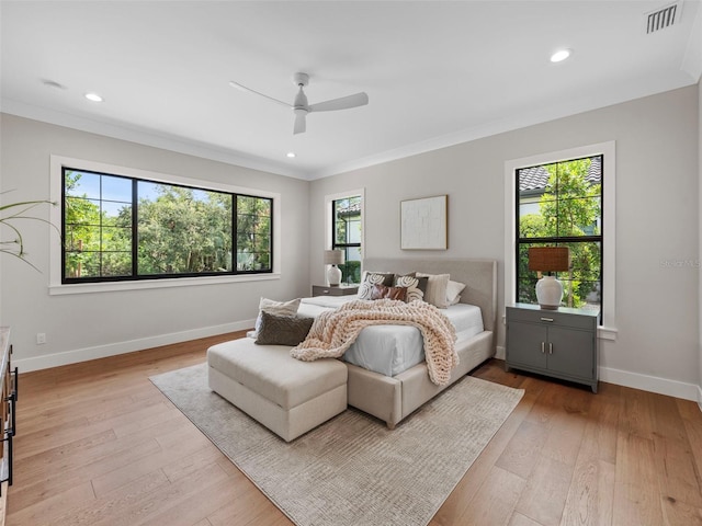 bedroom featuring crown molding, light hardwood / wood-style floors, and multiple windows