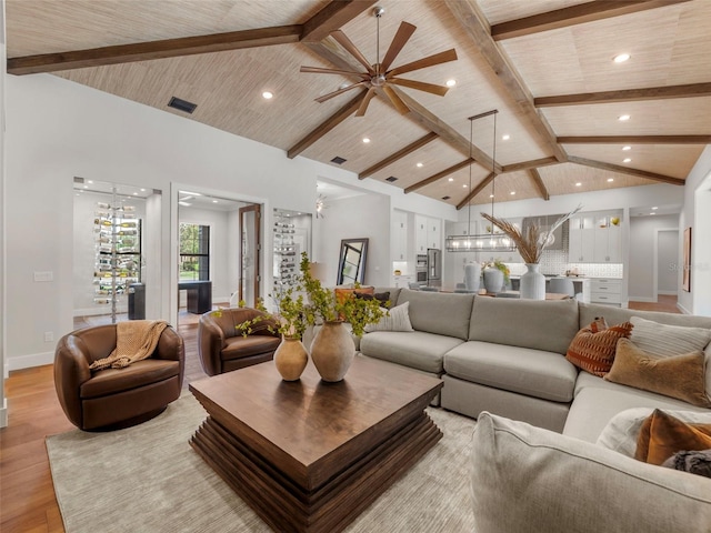 living room featuring beamed ceiling, a chandelier, high vaulted ceiling, and light hardwood / wood-style flooring