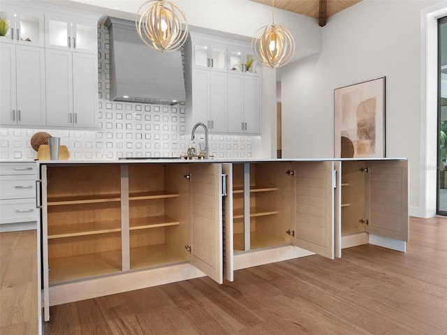 kitchen featuring white cabinetry, backsplash, light hardwood / wood-style flooring, and pendant lighting