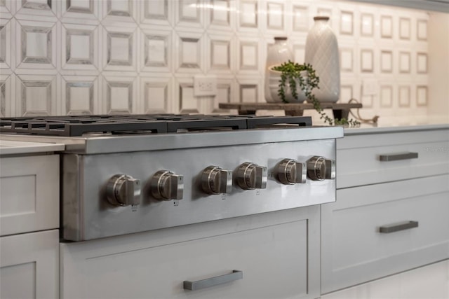 details featuring gas stovetop, white cabinetry, and backsplash