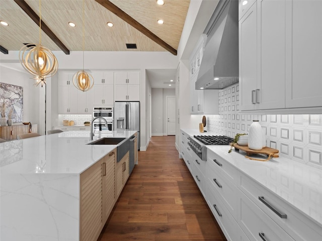 kitchen with white cabinetry, stainless steel appliances, decorative light fixtures, and wall chimney range hood