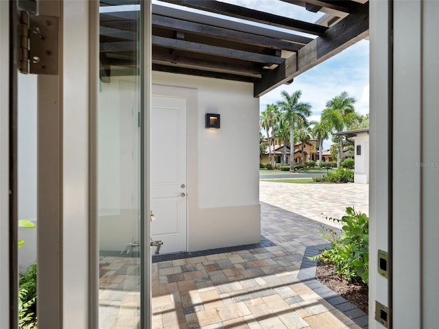 view of exterior entry with a pergola and a patio area