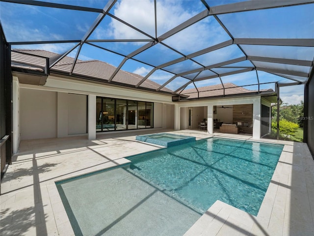 view of pool with an outdoor living space, ceiling fan, glass enclosure, and a patio area