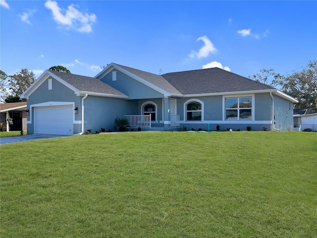 ranch-style home featuring covered porch, a front yard, and a garage