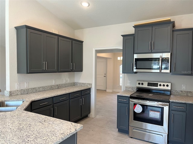 kitchen with sink, stainless steel appliances, light stone counters, vaulted ceiling, and light wood-type flooring