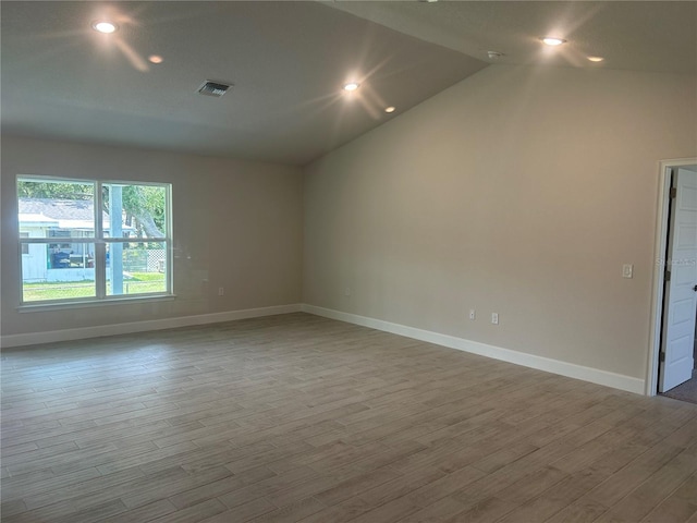 spare room featuring light hardwood / wood-style floors and vaulted ceiling