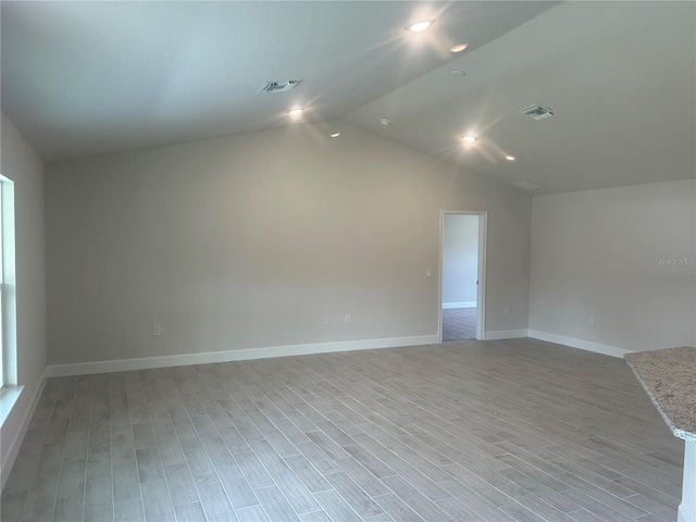 unfurnished room with light hardwood / wood-style flooring and lofted ceiling