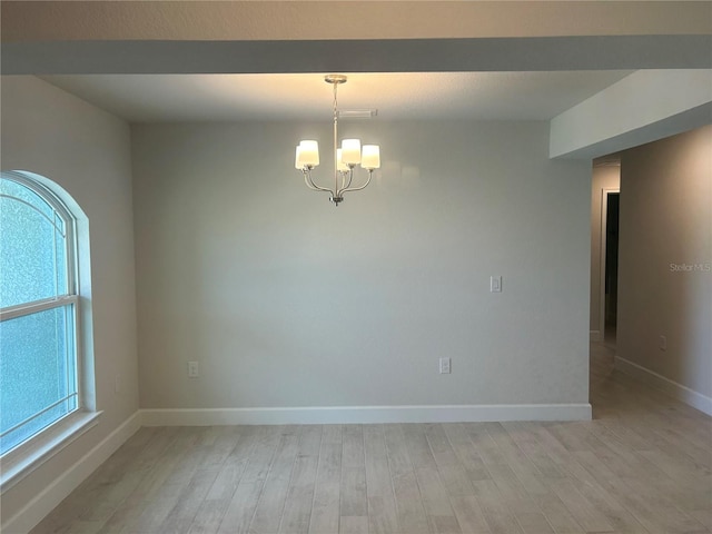 spare room with light hardwood / wood-style flooring and a notable chandelier